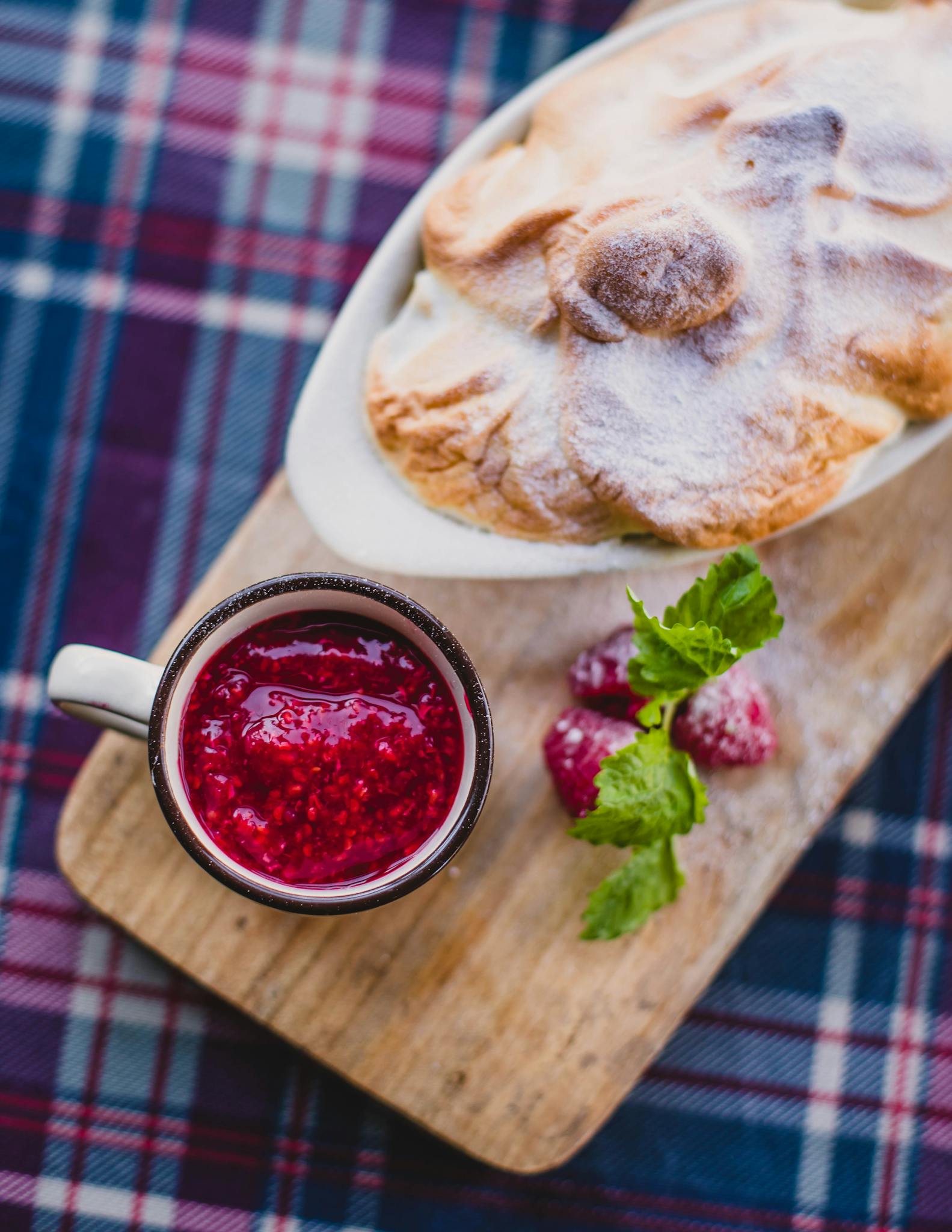 Delicious raspberry jam paired with a baked pastry on a rustic wooden board.